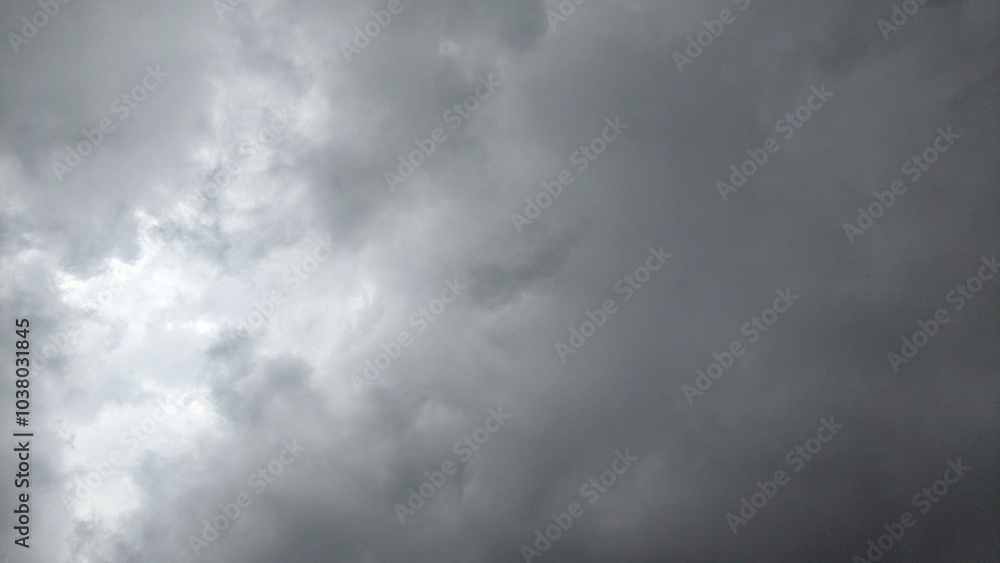A cloudy sky with dark, ominous clouds. The clouds are thick and appear to be moving quickly. There are faint streaks of light visible through the clouds. A cloudy sky with dark, ominous clouds. The clouds are thick and appear to be moving quickly. There are faint streaks of light visible through the clouds.