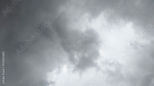 A cloudy sky with dark, ominous clouds. The clouds are thick and appear to be moving quickly. There are faint streaks of light visible through the clouds.