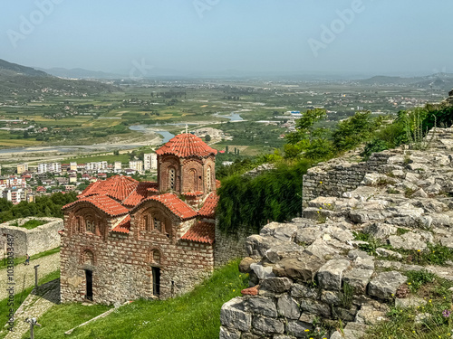 Byzantine Holy Trinity Church nestled within castle walls of Berat, Albania. Osum River flowing through valley surrounded by majestic mountain massif Shpirag. Red-tiled roof and dome. Natural beauty photo