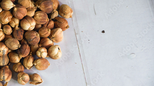 Close-up of dried cardamom pods, amomum kravanh, scattered on a white wooden surface, ideal for illustrating spice-related content, natural products, or culinary themes photo