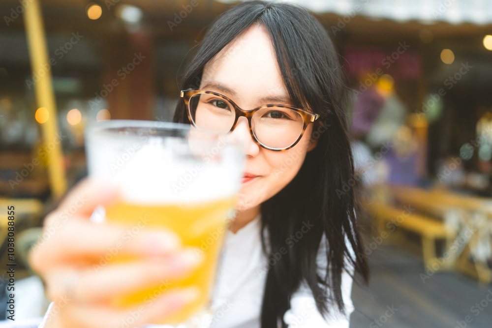 Portrait of young adult asian woman with eyeglasses drinking beer at restaurant Portrait of young adult asian woman with eyeglasses drinking beer at restaurant