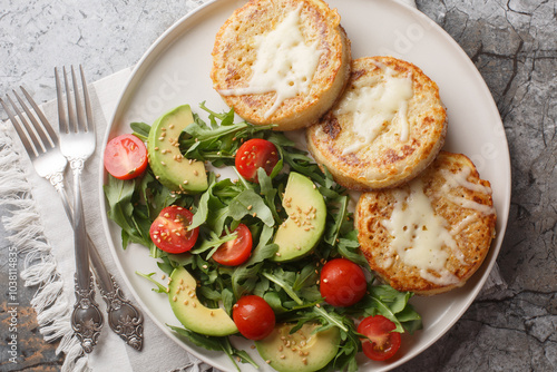 Fried crumpets in beaten egg with fresh vegetable salad for breakfast close-up in plate on table. Horizontal top view from above photo