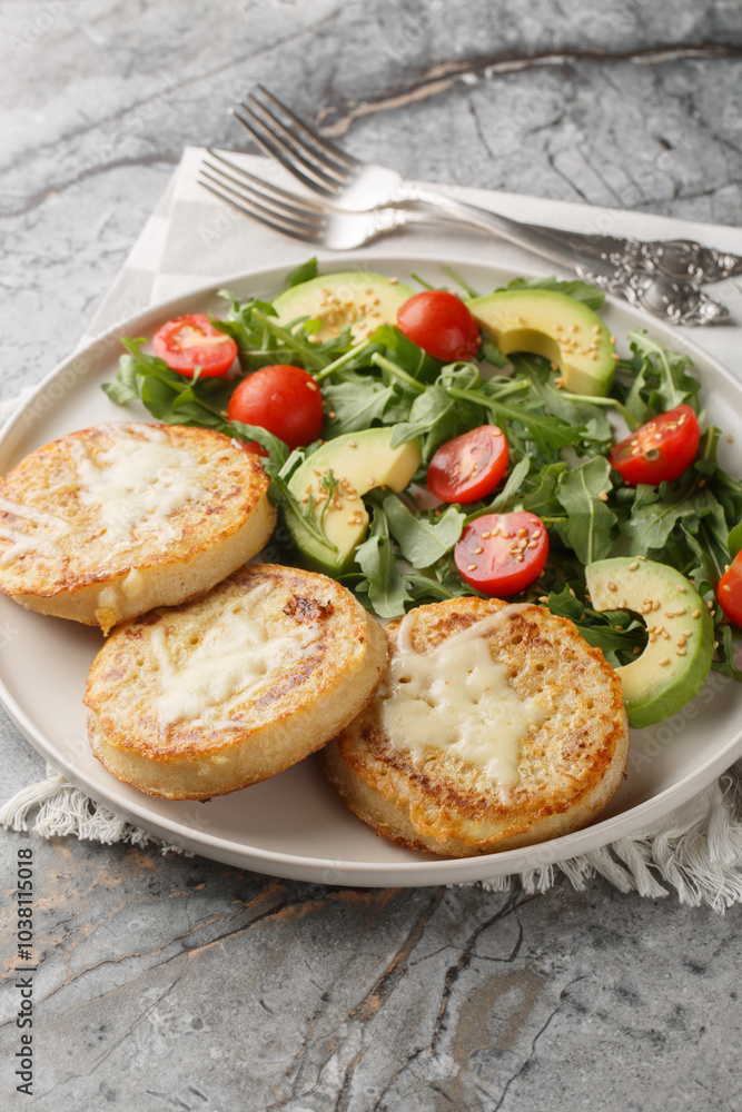 Eggy cheese crumpets with vegetables salad closeup on the plate on the table. Vertical Eggy cheese crumpets with vegetables salad closeup on the plate on the table. Vertical