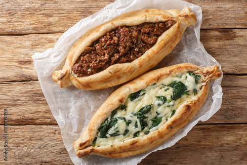 Obraz na płótnie Traditional turkish baked dish pide with ground meat, cheese, spinach and spicy close-up on wooden board on table. Horizontal top view from above w salonie