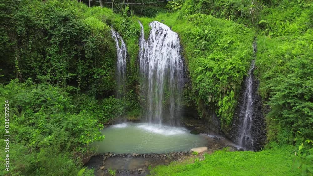 A man camping under a beautiful waterfall in the middle of green vegetation, amidst trees and forests A man camping under a beautiful waterfall in the middle of green vegetation, amidst trees and forests
