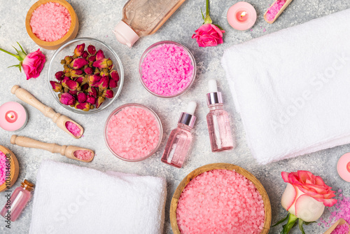 Sea salt for bath with aroma and rose flowers on textured wooden background. Pink sea salt. Spa treatments. Natural salt with herbs and essential oils. skincare concept. Meso for text. Copy space photo