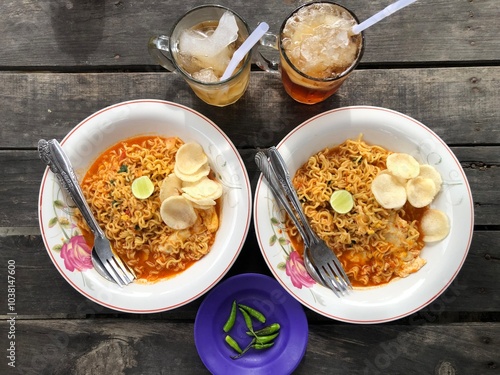 Indomie Boiled or Soto Flavored Instant Boiled Noodles, Indonesian Instant Noodles with Boiled Eggs, Tomatoes and Lime Slices photo