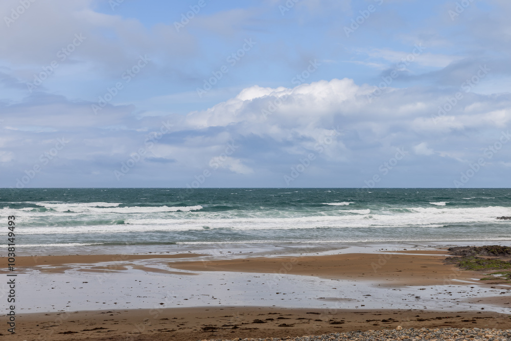 Sunny day at Strandhill beach, Ireland, with gentle waves crashing on wet sand and a blue sky with fluffy clouds above the ocean Sunny day at Strandhill beach, Ireland, with gentle waves crashing on wet sand and a blue sky with fluffy clouds above the ocean
