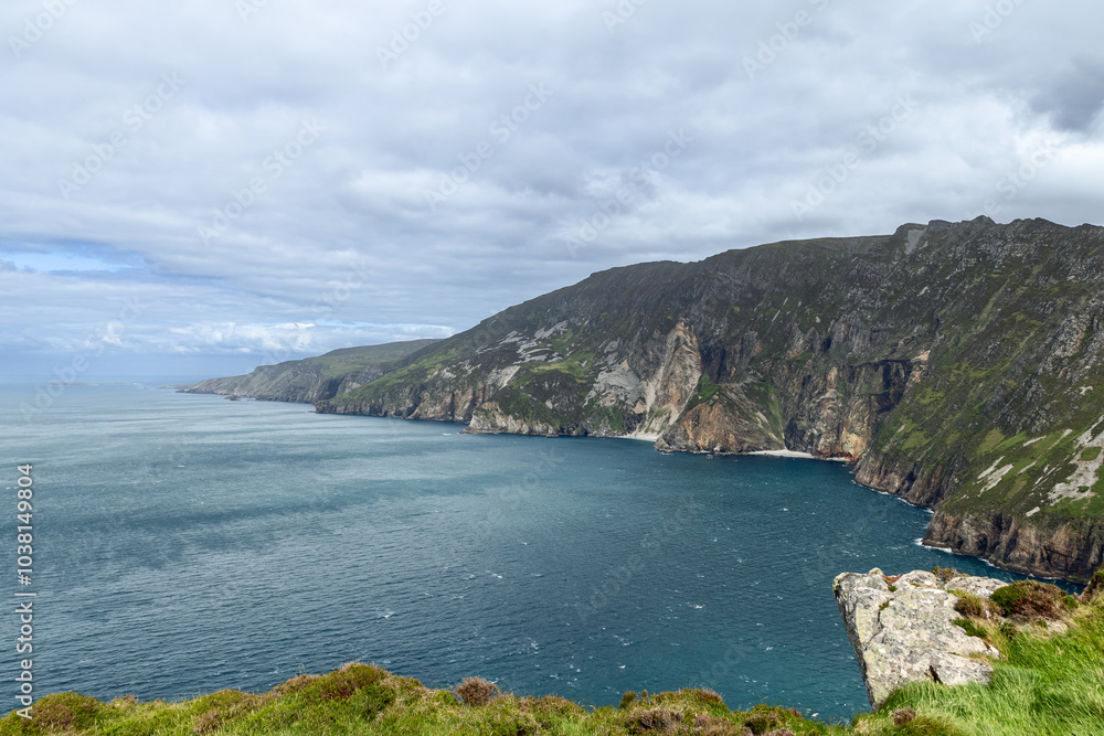 Fototapeta premium A view of the towering cliffs at Slieve League, Ireland, with steep rock faces and the vast Atlantic Ocean stretching into the distance
