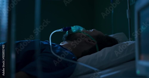 Young individual in hospital bed using oxygen mask.