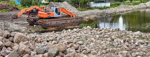 Fotografie Amphibious Excavator Working on a Pond