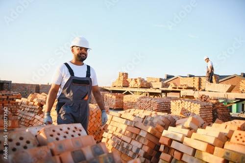 Portrait of an Indian construction worker in overalls and a hard hat at a construction site photo