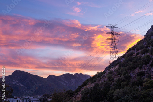 Majestic sunset over mountains with power lines silhouetted against vibrant sky