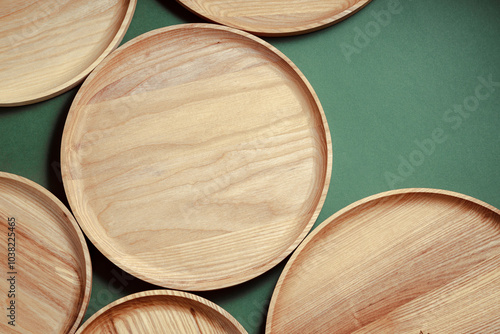 Wooden flat plates on a green background. The concept of ecological tableware. Products for modern kitchen. Zero emissions. photo