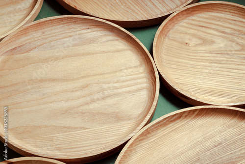 Wooden flat plates on a green background. The concept of ecological tableware. Products for modern kitchen. Zero emissions. photo