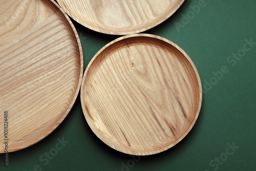 Wooden flat plates on a green background. The concept of ecological tableware. Products for modern kitchen. Zero emissions. photo