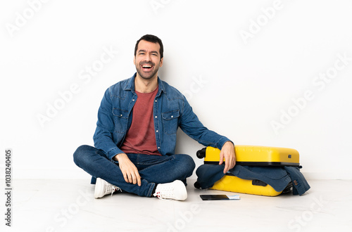 Caucasian handsome man with a suitcase full of clothes sitting on the floor at indoors laughing