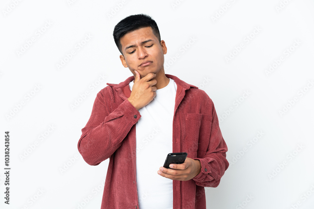 Young Ecuadorian man isolated on white background using mobile phone and thinking Young Ecuadorian man isolated on white background using mobile phone and thinking