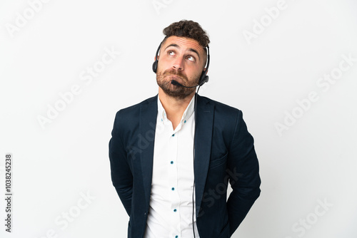 Obraz na płótnie Telemarketer man working with a headset isolated on white background and looking up