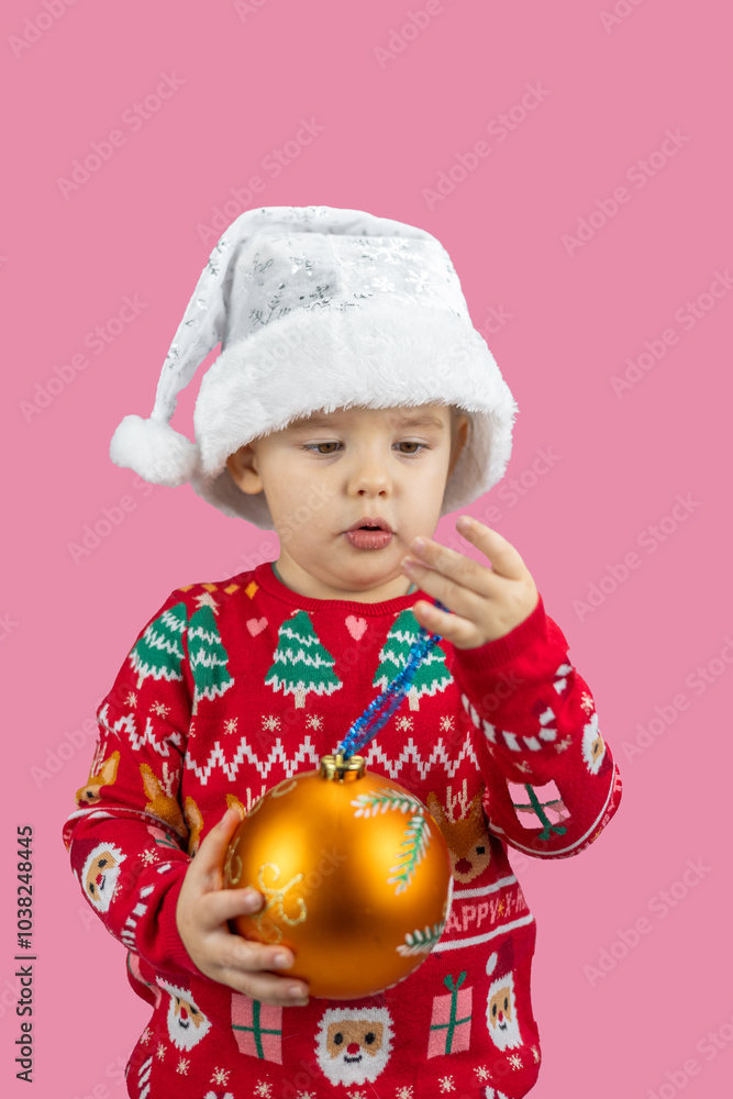 Cute baby girl in festive clothes holding golden ornament capturing holiday joy and wonder on cozy pink background. Child in Christmas clothes looking surprised on pink background. Cute baby girl in festive clothes holding golden ornament capturing holiday joy and wonder on cozy pink background. Child in Christmas clothes looking surprised on pink background.