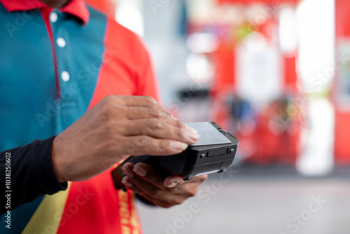 Hand of cashier hold credit card reader with blurry gas station background. Credit card payment. Buy and sell products & service. The concept of payment in gas station. photo