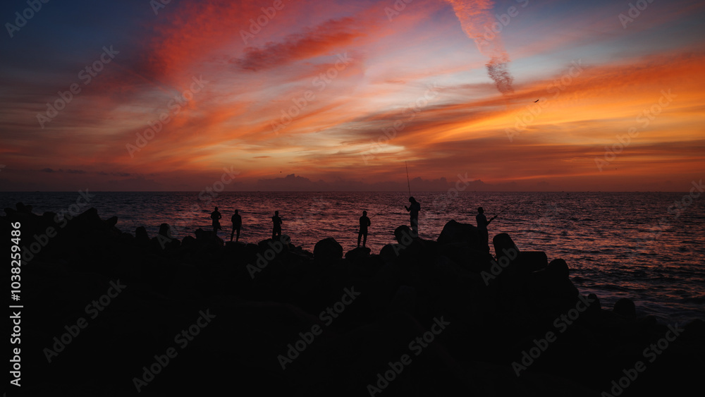 People fishing at the sea during sunset