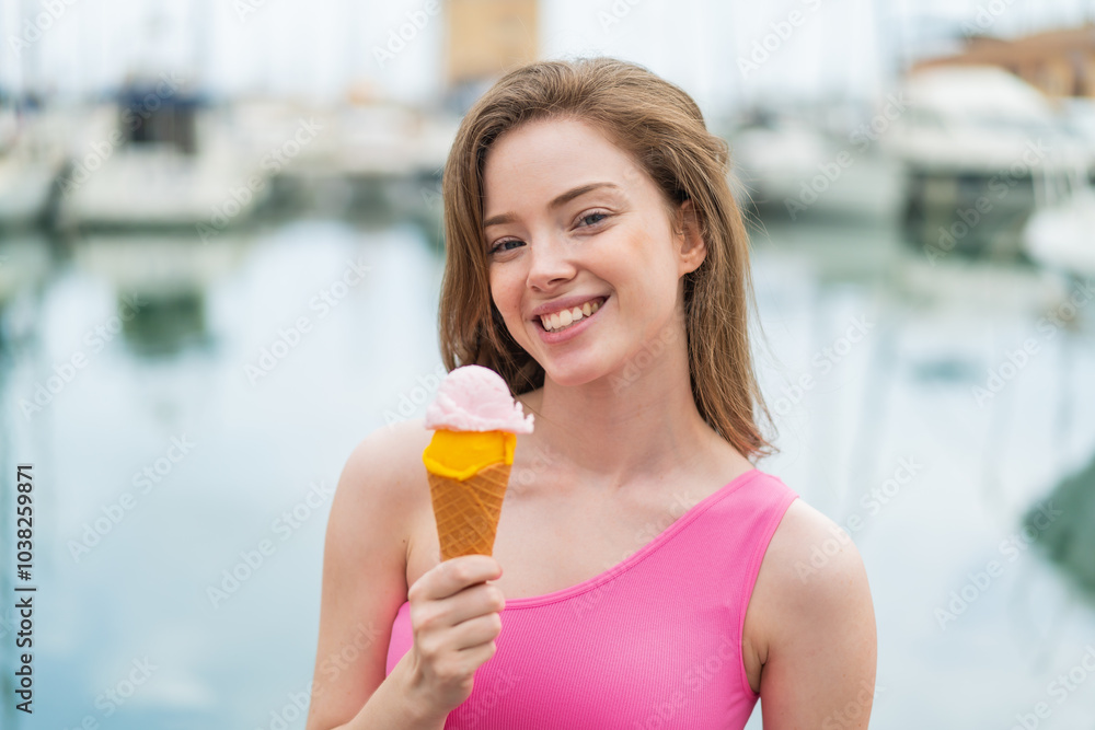 Young redhead woman with a cornet ice cream at outdoors smiling a lot Young redhead woman with a cornet ice cream at outdoors smiling a lot