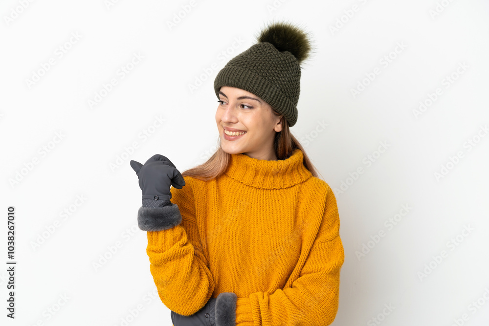 Young girl with winter hat isolated on white background pointing to the side to present a product Young girl with winter hat isolated on white background pointing to the side to present a product
