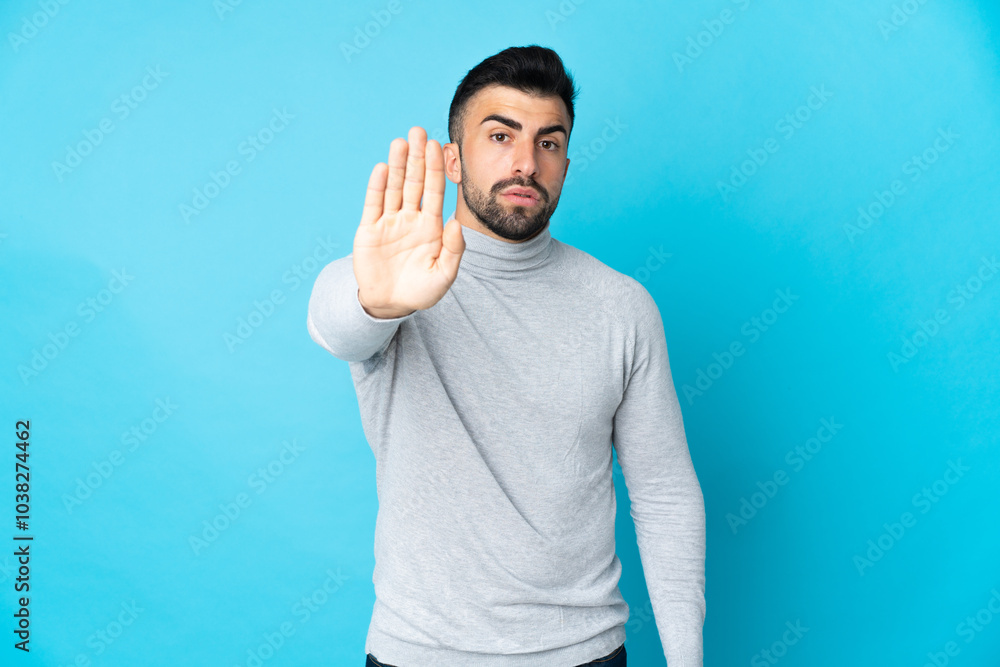 Caucasian man over isolated blue background making stop gesture Caucasian man over isolated blue background making stop gesture