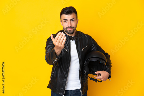 Caucasian man with a motorcycle helmet over isolated yellow background inviting to come with hand. Happy that you came