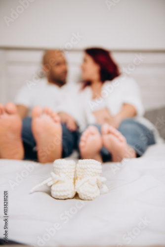 The Couple is lying in the bedroom with a small babies knitted socks.