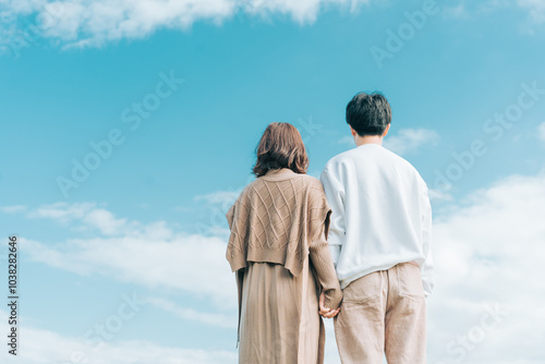 Bild auf Leinwand 秋の青空を見ながら寄り添う男女の後ろ姿