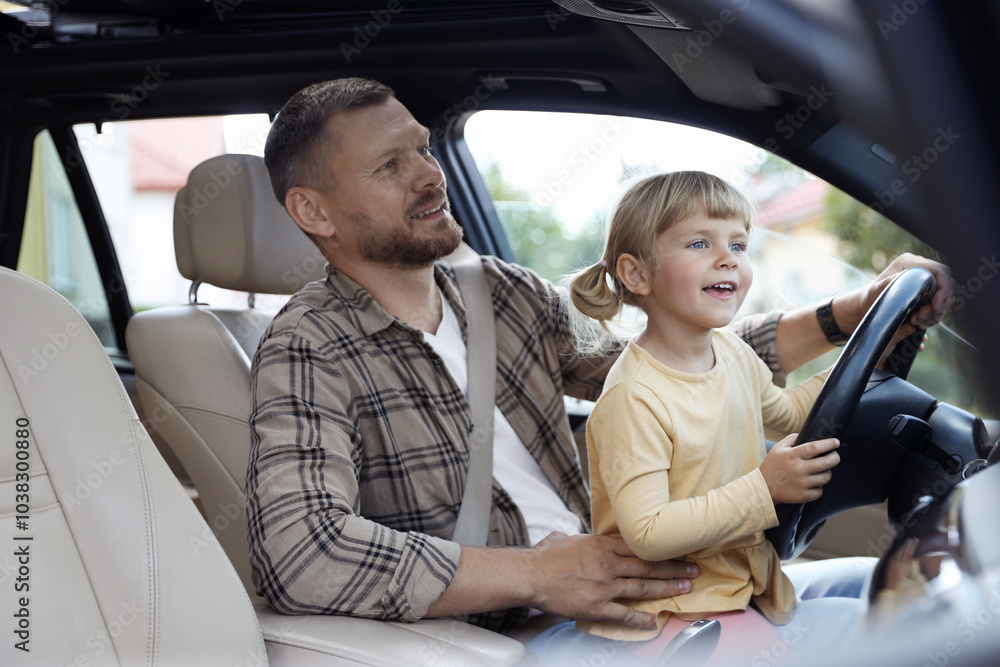 Man with his daughter holding steering wheel inside car Man with his daughter holding steering wheel inside car