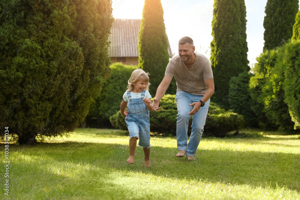 Fototapeta premium Father and his daughter spending time together on green lawn in park