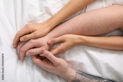 Lovely couple holding hands in bed, top view.