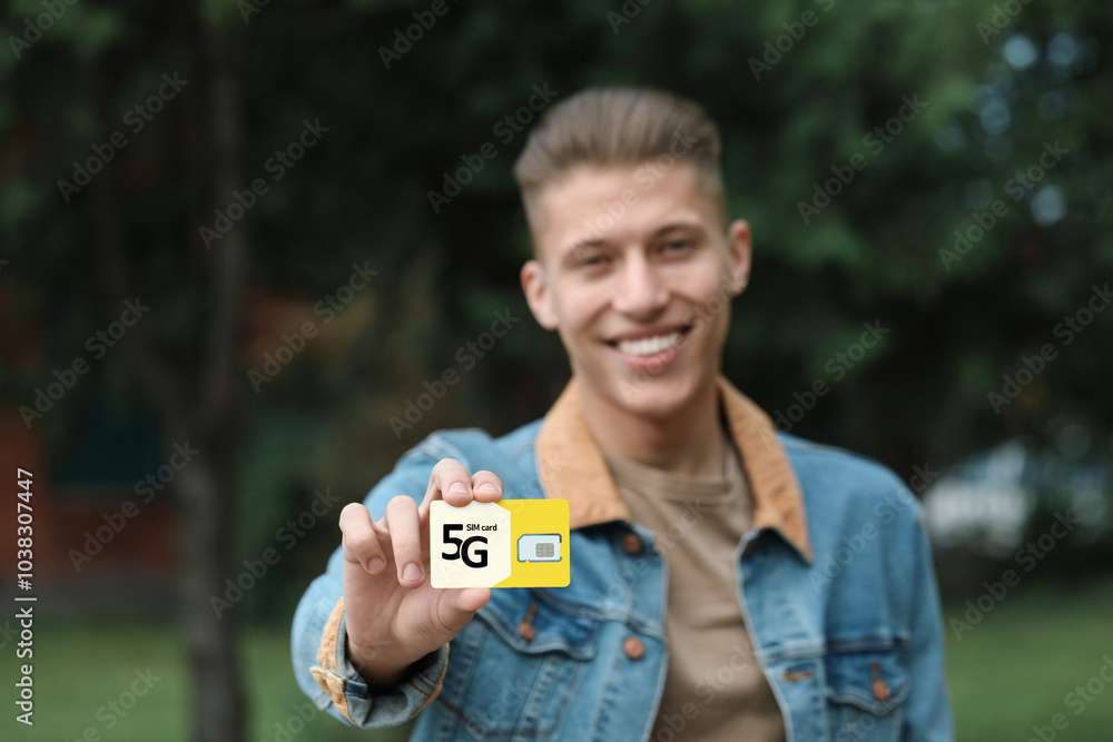 Happy man with 5G SIM card outdoors, selective focus Happy man with 5G SIM card outdoors, selective focus