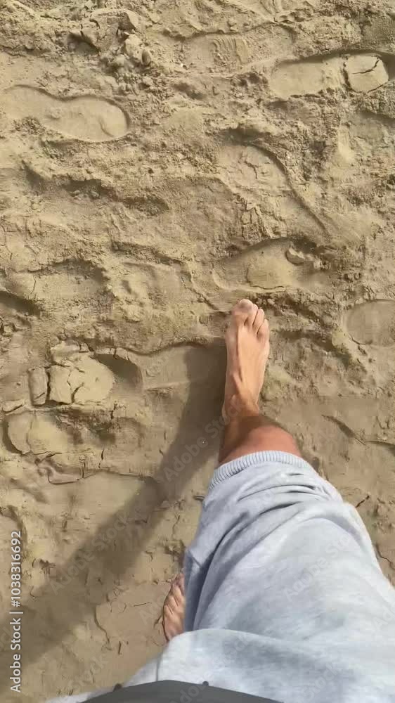Vertical 4K video of a man walking barefoot from the beach sand into the sea, with a view of the horizon and sky in the background. Vertical 4K video of a man walking barefoot from the beach sand into the sea, with a view of the horizon and sky in the background.