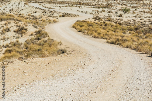 Dirt road in arid desolate landscape on a sunny day.