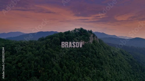 Brasov symbol sign on top of the Tampa mountain. Big white letters in the mountain forest. Old city Brasov, Kronstadt, Romania. Aerial view of Brasov sign on the hill. Mountain pine forest sunset.