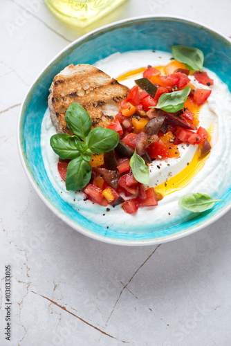 Ricotta dipping sauce with chopped tomatoes and basil in a turquoise bowl, vertical shot on a white granite surface, middle closeup