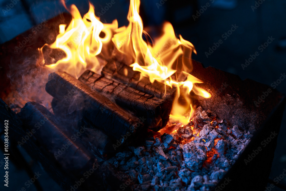 Obraz premium Burning wood for cooking on the grill. Tongues of flame, smoke, coal and ash. Burning hot charcoal. The tongues of flame and ashes. Forge horn, brazier. 