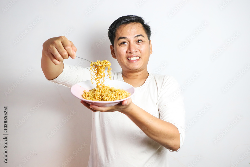 Adult Asian man showing surprised expression while eating noodle Adult Asian man showing surprised expression while eating noodle