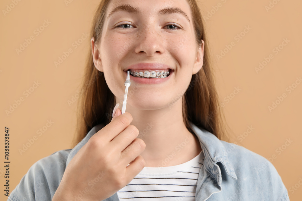 Girl with braces cleaning teeth with interdental brush on beige background Girl with braces cleaning teeth with interdental brush on beige background