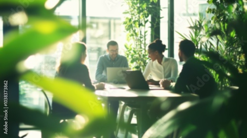 This blurred image captures a group of professionals in a well-lit office, engaged in a collaborative discussion, with plants adding a refreshing, natural touch.