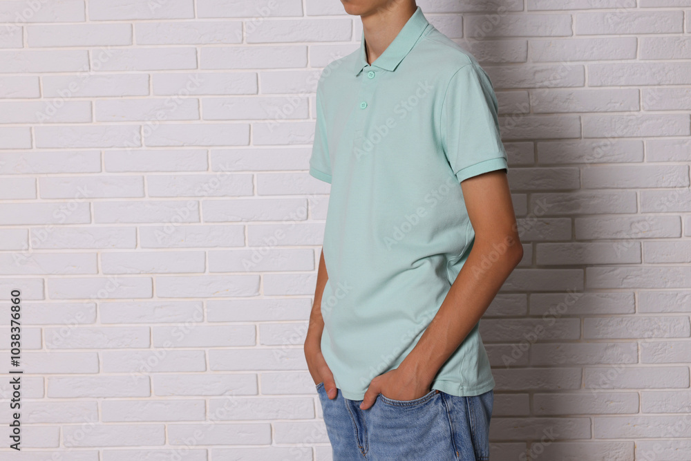 Teenage boy wearing light green t-shirt near white brick wall, closeup. Space for text Teenage boy wearing light green t-shirt near white brick wall, closeup. Space for text