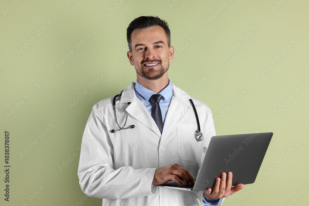 Smiling doctor with stethoscope using laptop on olive background Smiling doctor with stethoscope using laptop on olive background