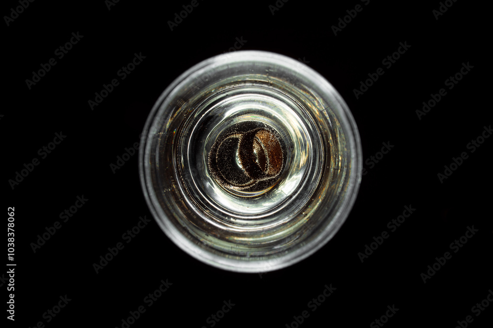 Wedding rings in a glass of champagne. Beverage gas bubbles around the jewelry. Isolate of glasses with champagne on a black background. Unique design elements for invitation, wedding cards. Wedding rings in a glass of champagne. Beverage gas bubbles around the jewelry. Isolate of glasses with champagne on a black background. Unique design elements for invitation, wedding cards.