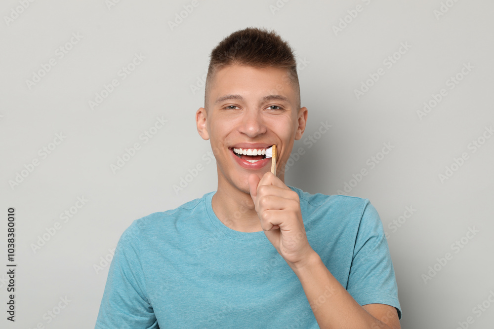 Fotografie Young man brushing his teeth on gray background