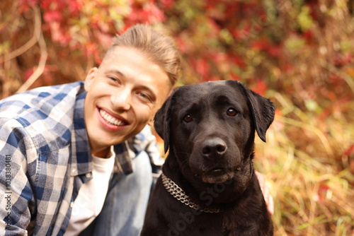 Smiling man with cute dog outdoors on autumn day