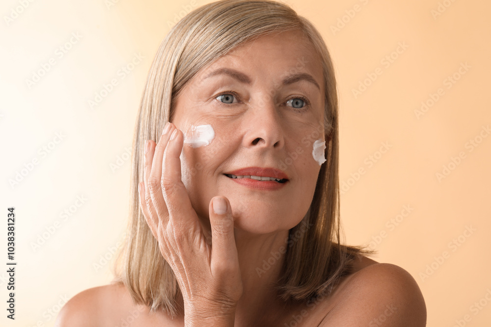 Senior woman applying face cream on beige background Senior woman applying face cream on beige background